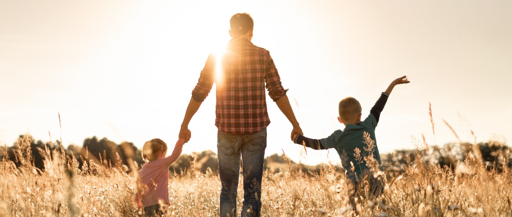 father walking through a field with his children