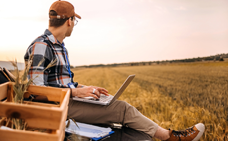 Farmer with laptop in a field.