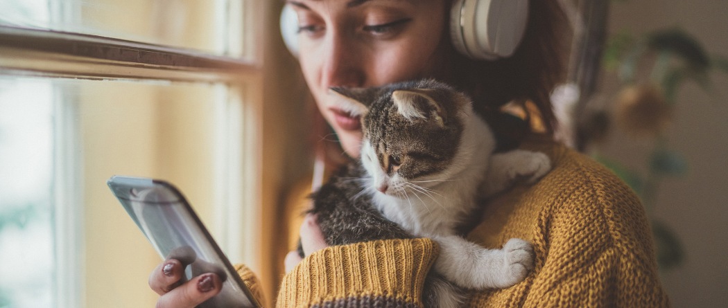 a woman holding a mobile phone and her kitten